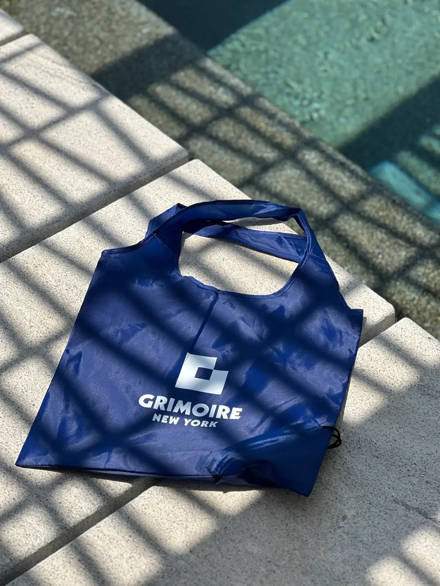 Grimoire NYC branded tote bag by the pool at Rochari Hotel Mykonos