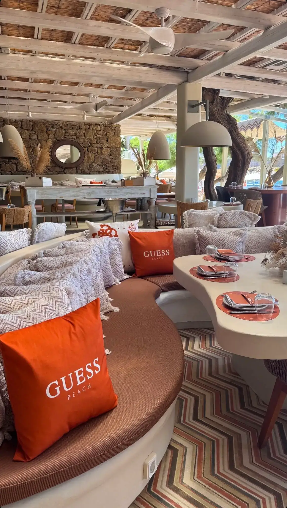 GUESS-branded VIP area at Kalua Beach Club Mykonos with orange branded pillows